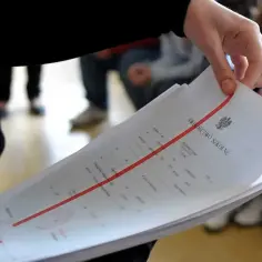 Dłoń trzyma stos świadectw szkolnych. Czy religia wlicza się do średniej? To pytanie nurtuje wielu uczniów.
