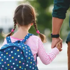 Dziewczynka z warkoczami i plecakiem idzie za rękę z tatą. Może to być początek dnia, ale dla niej to walka z fobią szkolną.