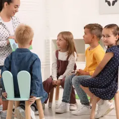 Nauczycielka czyta książkę grupie dzieci. Czy w grupie przedszkolnej może być 26 dzieci? Ta scena sugeruje mniejszą grupę.