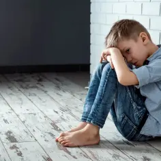 Chłopiec skulony w kącie, smutny i samotny. Czy to nękanie w szkole? Paragraf o tym problemie.