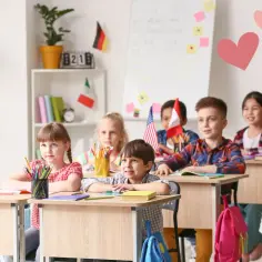 Uczniowie z zaangażowaniem uczestniczą w zajęciach dydaktyczno wyrównawczych. Nauczycielka z uśmiechem obserwuje ich postępy.