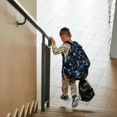 Chłopiec z plecakiem wspina się po schodach. Każdy uczeń to przyszłość, a subwencja oświatowa na ucznia wspiera tę drogę.