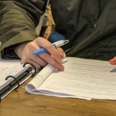 Uczeń z długopisem w dłoni, pochylony nad notatkami i zadaniami matematycznymi. Myśli: "co jak nie zdam matury ustnej?".