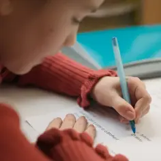 Dziewczynka pisze wypracowanie, starając się o jak najlepsze oceny z zachowania.