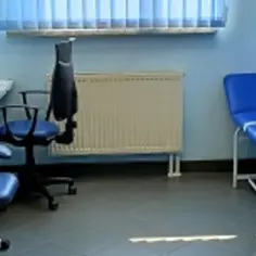 Przytulny gabinet pielęgniarki szkolnej z niebieskimi meblami, kozetką i sprzętem medycznym.