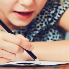 Dziecko zmagające się z dysleksją, skupione na pisaniu. Widoczne objawy trudności w nauce.