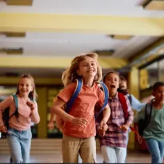Radosne dzieci biegną korytarzem szkolnym, z plecakami na plecach. Czy 22 grudnia jest wolne od szkoły? Pewnie tak, skoro tak się cieszą!