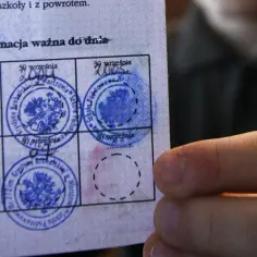 Widok na legitymację szkolną z pieczątkami. Widać daty i okrągłe pieczątki z godłem Polski.