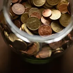 Skarbonka pełna monet euro, symbolizująca odprawę dla nauczyciela przechodzącego na świadczenie kompensacyjne.