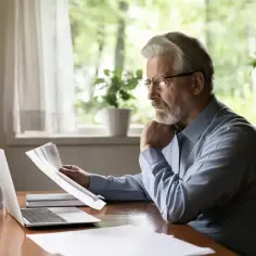 Emerytowany nauczyciel analizuje dokumenty, rozważając ponowne zatrudnienie u tego samego pracodawcy.