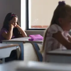 Smutna dziewczynka z opaską na głowie siedzi przy ławce, myśląc o ocenie niedostatecznej na półrocze.