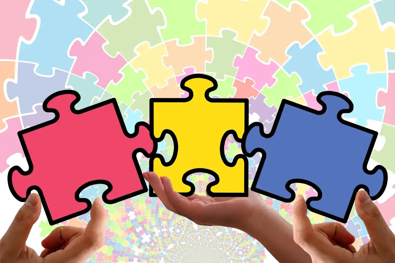 Różne dłonie składają puzzle. Kto może prowadzić rewalidację w szkole? Specjaliści, którzy potrafią połączyć wiedzę i wsparcie.