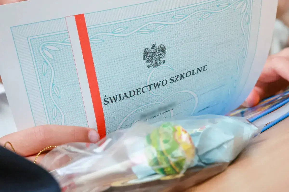 Świadectwo szkolne z orłem i biało-czerwonym paskiem. Czy doradztwo zawodowe jest na świadectwie? W tle słodycze.