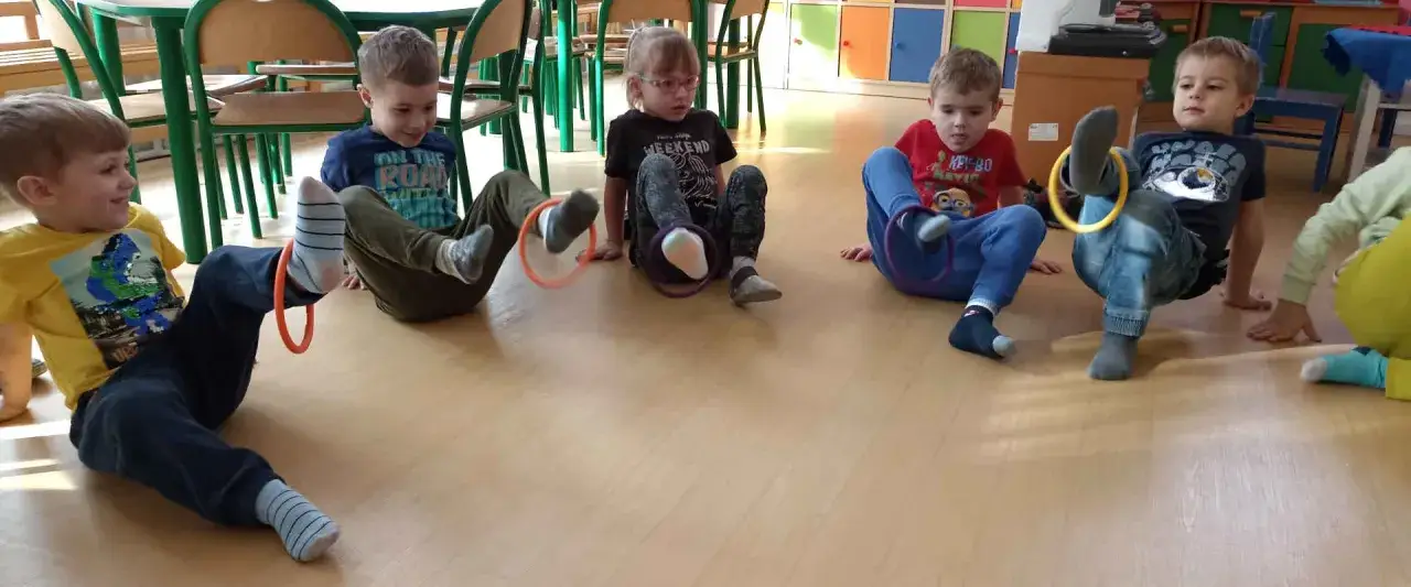 Dzieci ćwiczą z obręczami, realizując kierunki polityki oświatowej w przedszkolu poprzez zabawę ruchową.