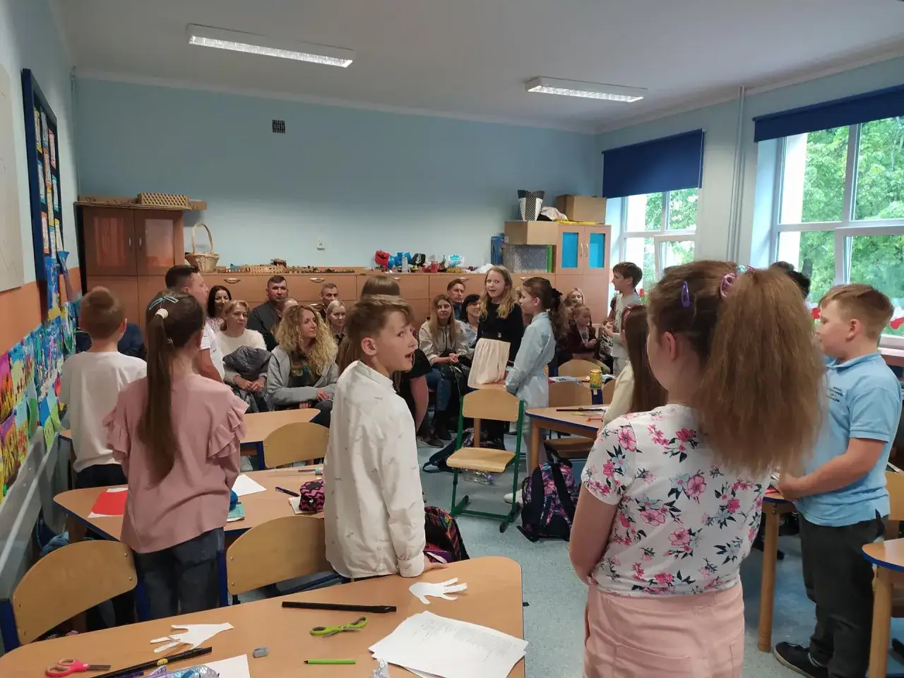 Dzieci i dorośli uczestniczą w lekcji wychowanie do życia w rodzinie. Wszyscy słuchają, jak chłopiec w białej koszuli opowiada.