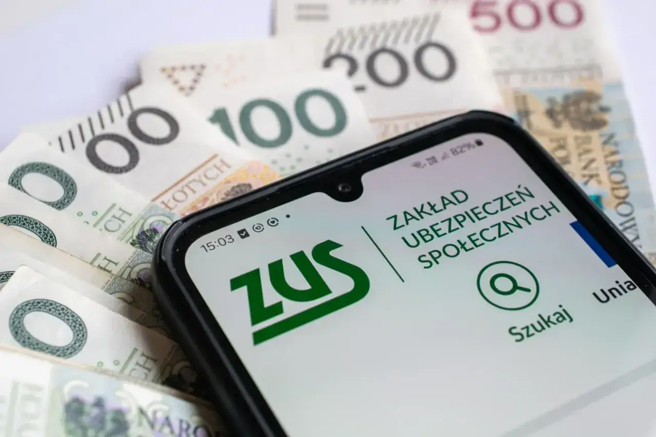 ZUS na ekranie telefonu, obok banknotów. Przygotowanie do odprawy dla nauczyciela przechodzącego na świadczenie kompensacyjne.