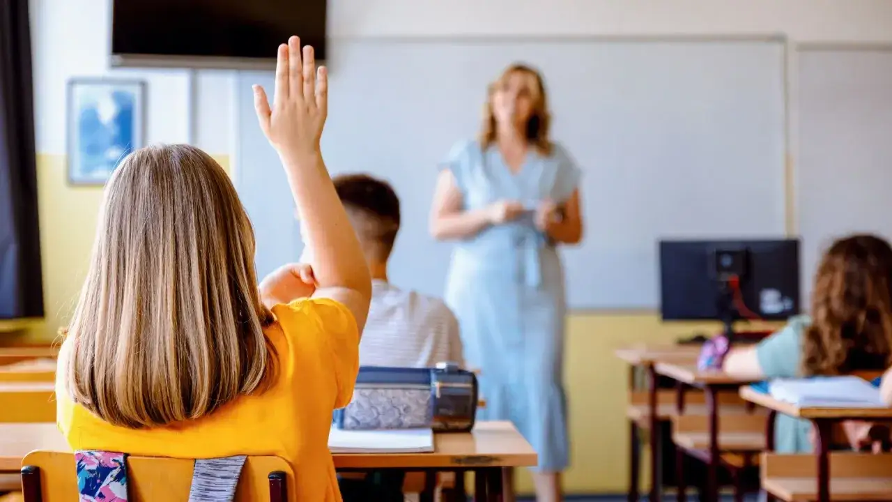 Uczennica z podniesioną ręką w klasie. Nauczycielka stoi z przodu. Czy po radzie pedagogicznej można zmienić oceny?